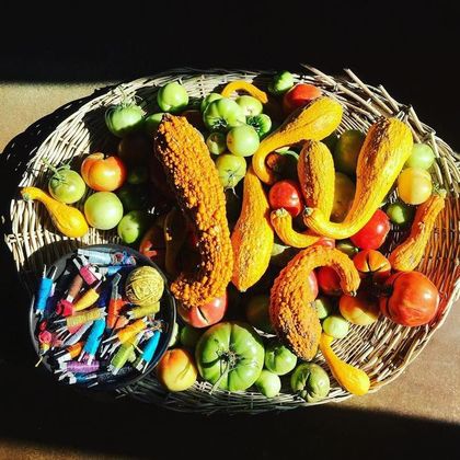 A basket heaped with tomatoes, peppers and corn