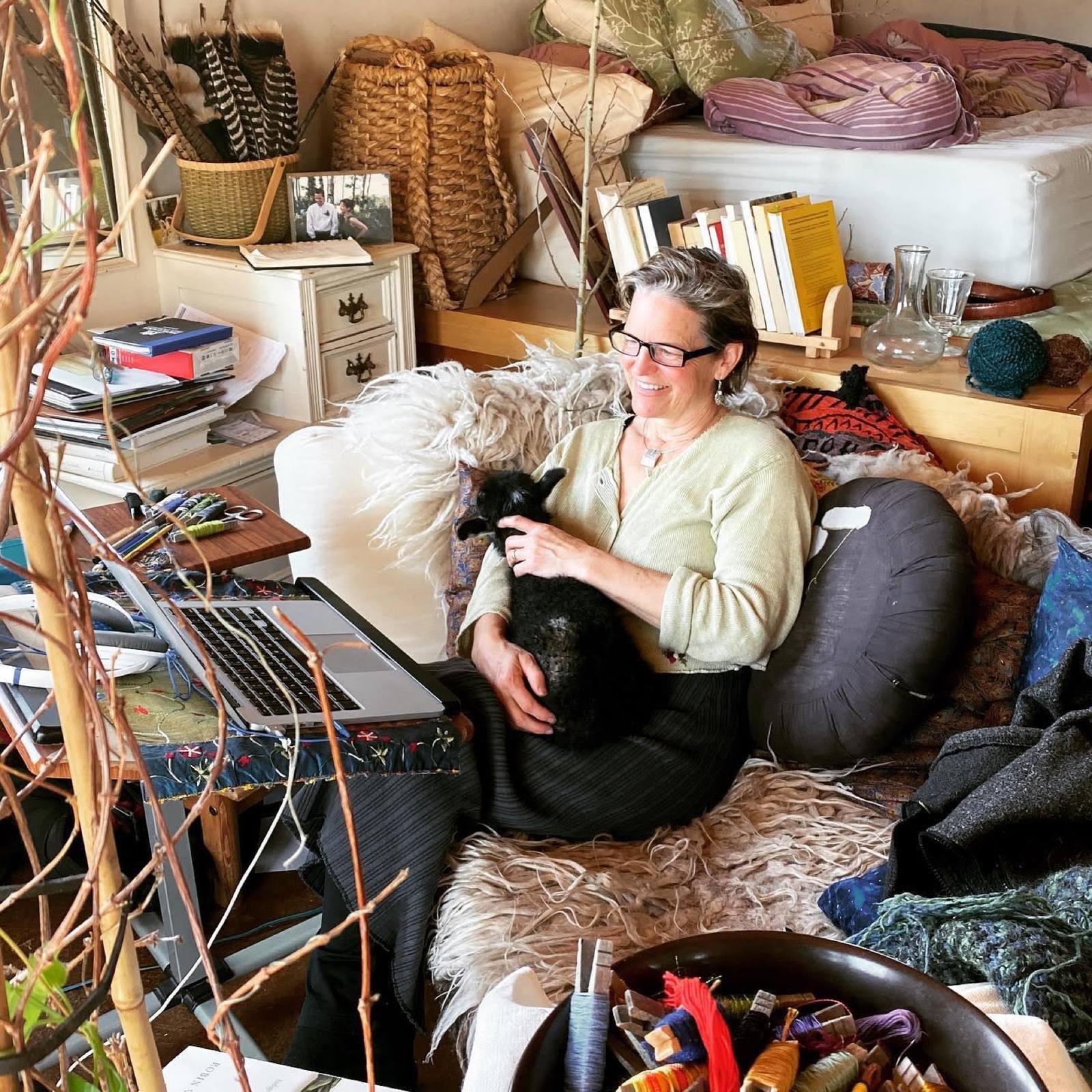 Lorca at home with a black lamb on her lap, wool and books all around